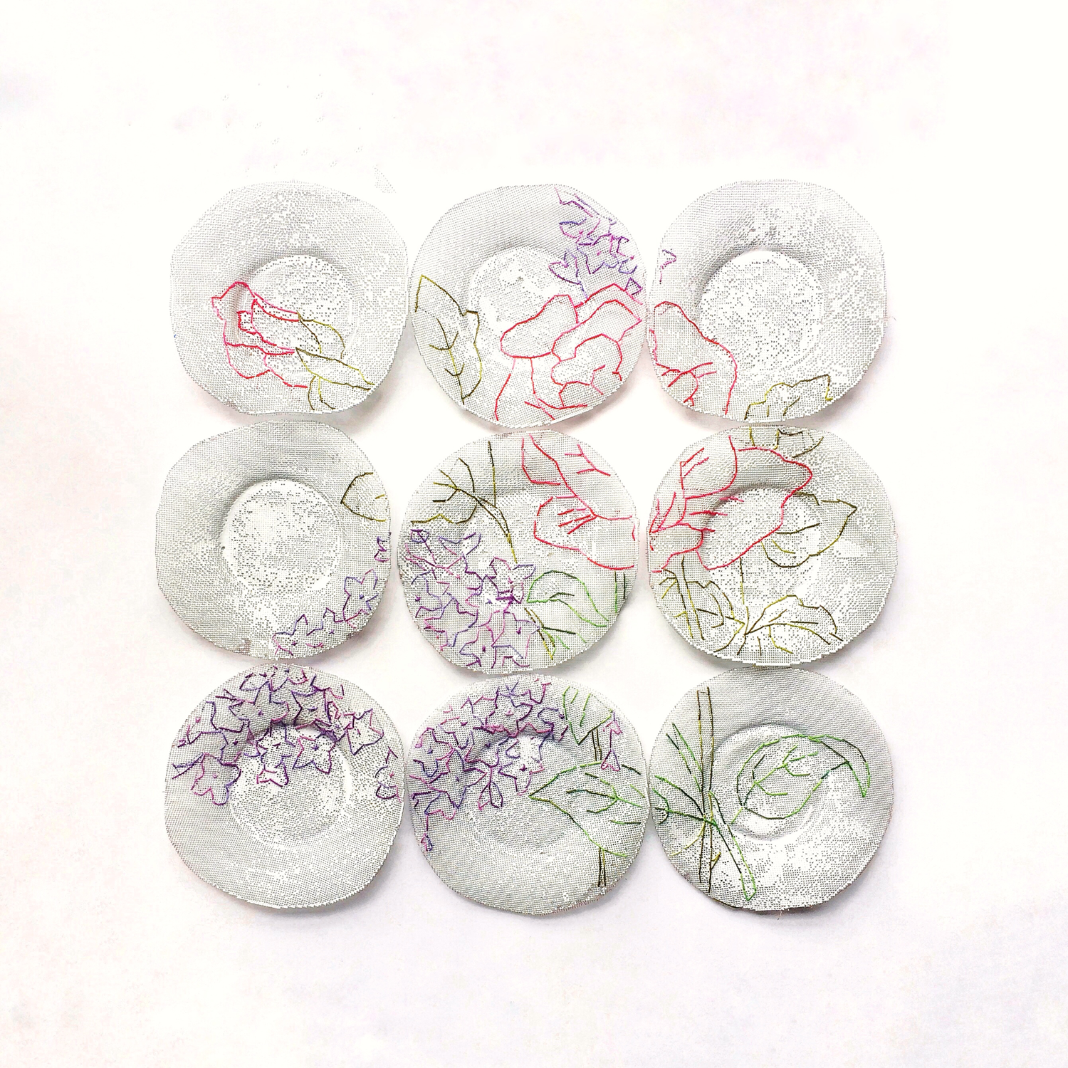 Nine enamelled copper mesh plates with stitching of flowers