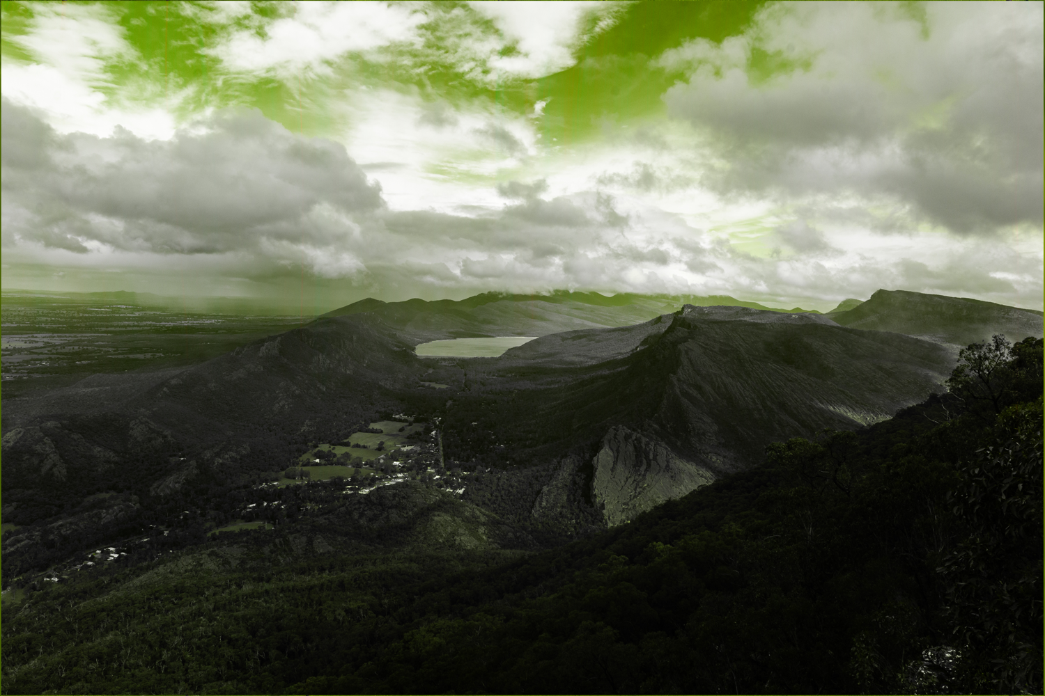 Colour photograph of mountainous landscape, polluted with tinted lime lighting.