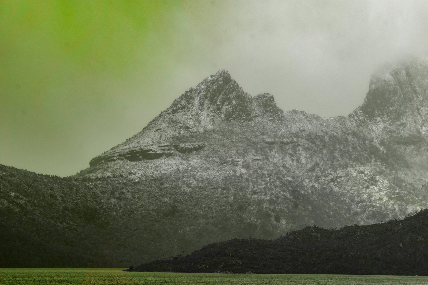 Colour photograph of mountainous landscape, polluted with tinted lime lighting.