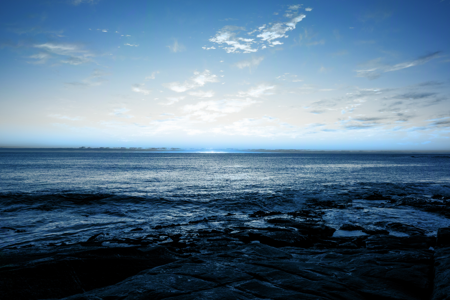 Colour photograph of sea and horizon, with tinted blue lighting.