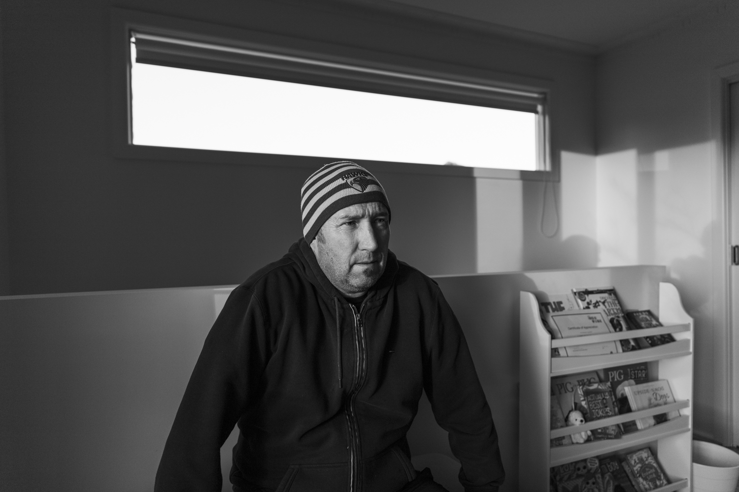 Black and white image of a portrait of a man sitting in a domestic environment.