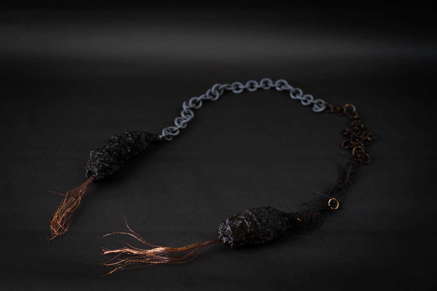 two black cocoons linked by dark heavy chain