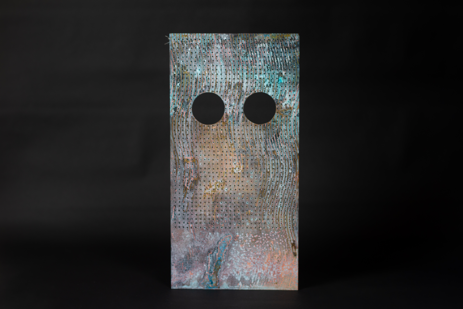 Patinated brass sheet with eye holes cut out