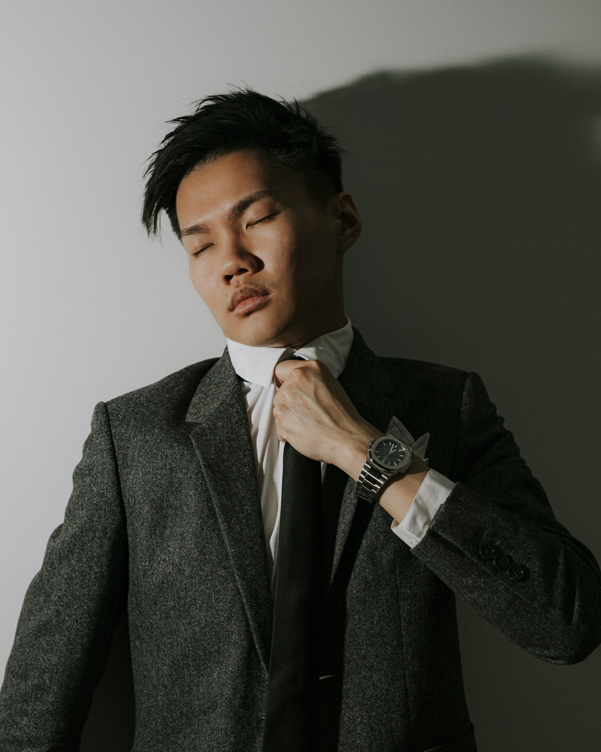 Colour photograph of a self-portrait the artist  in a two piece suit with hands strangling their neck with tie.