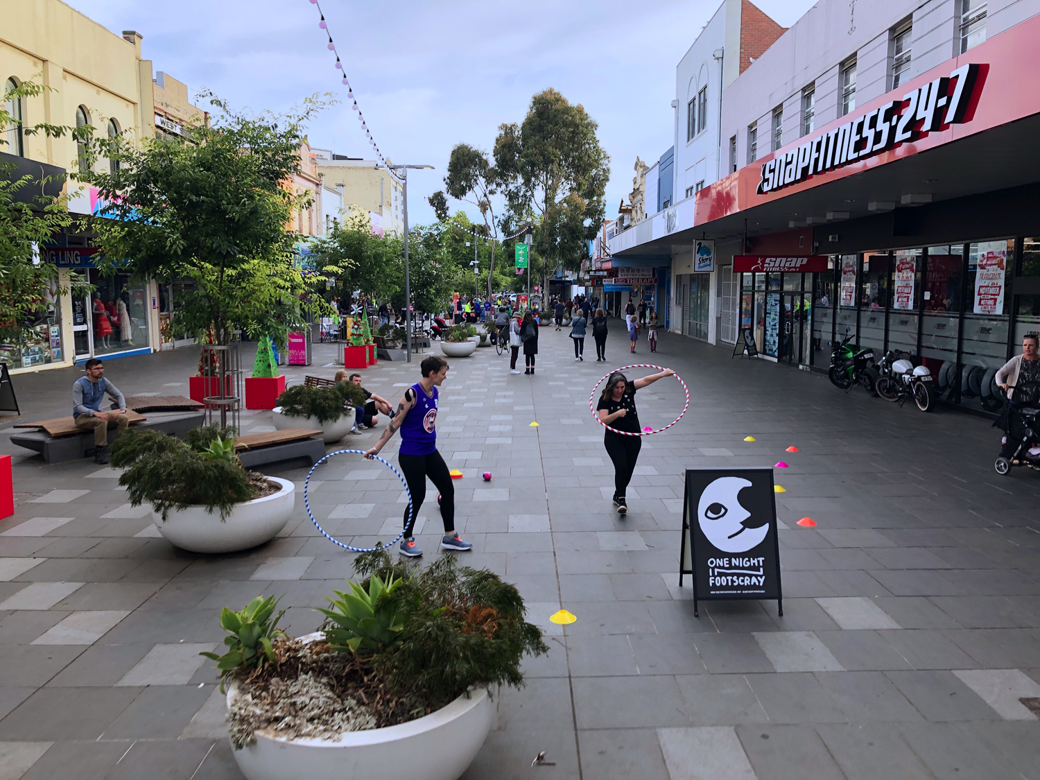 Two performers with hula hoops surrounded by colourful cones in Nicholson Street Mall Footscray.