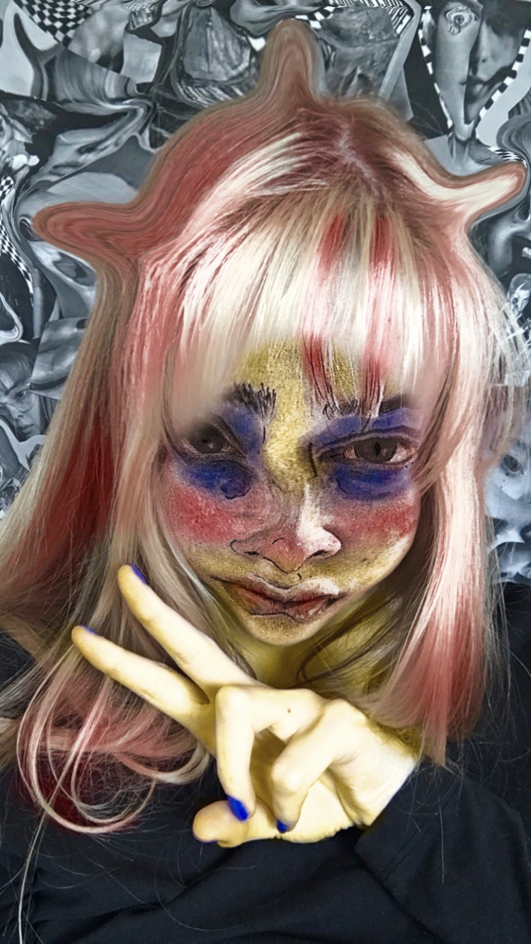 They are wearing black and displaying a two finger 'peace' sign with their left hand. The background is greyscale distorted collage material, featuring obscured faces and checkers. 