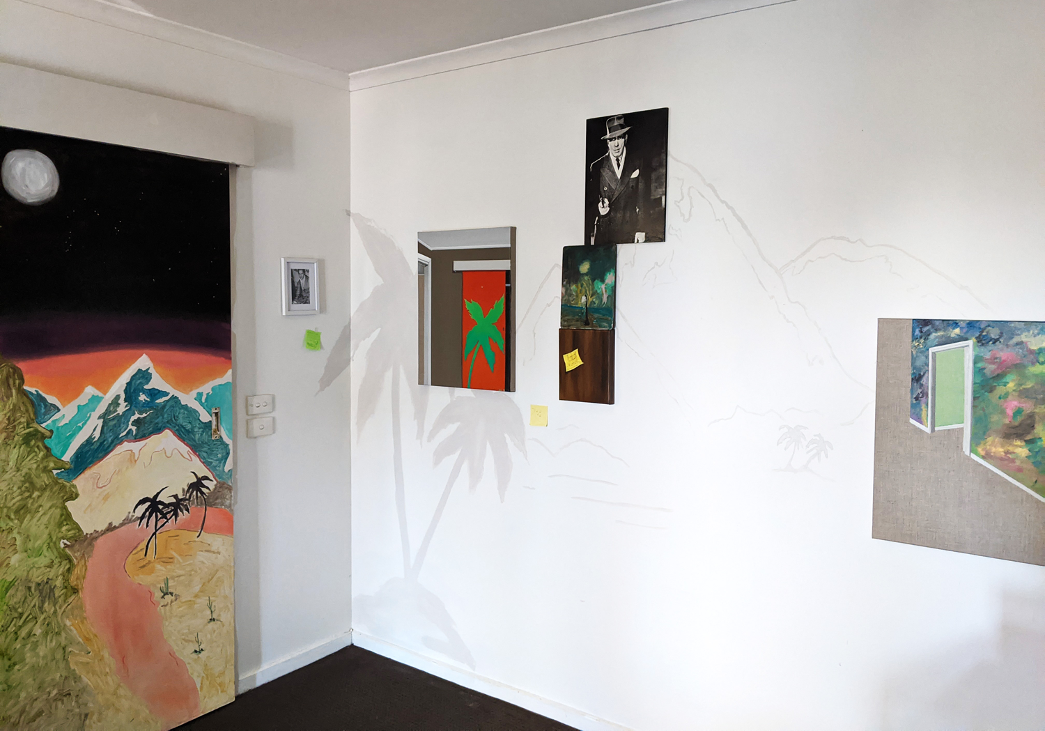 A domestic scene of a landscape explored upon the walls of an individuals home. Shadows of palm trees and mountains are across the wall with collaged images  of another interior space