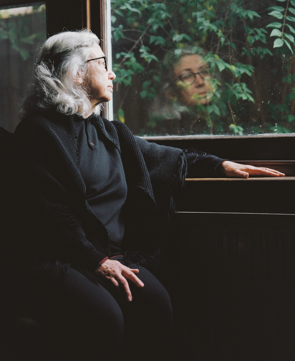 Colour photograph of a portrait of the artist's mother staring out a window. 