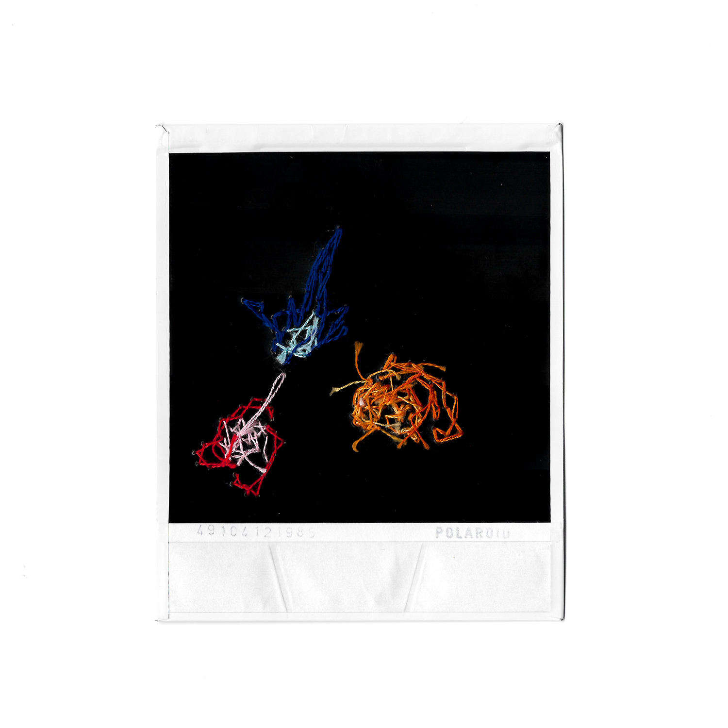 Underside of polaroid photograph with colourful embroidery sewn into it.