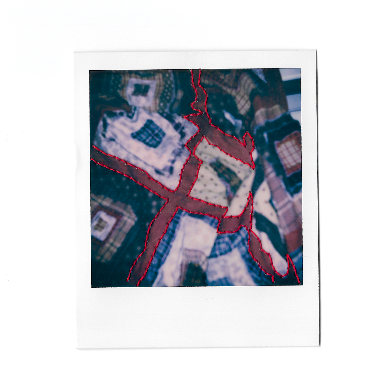Polaroid photograph depicting image of patchwork quilt with colourful embroidery sewn into the photograph.