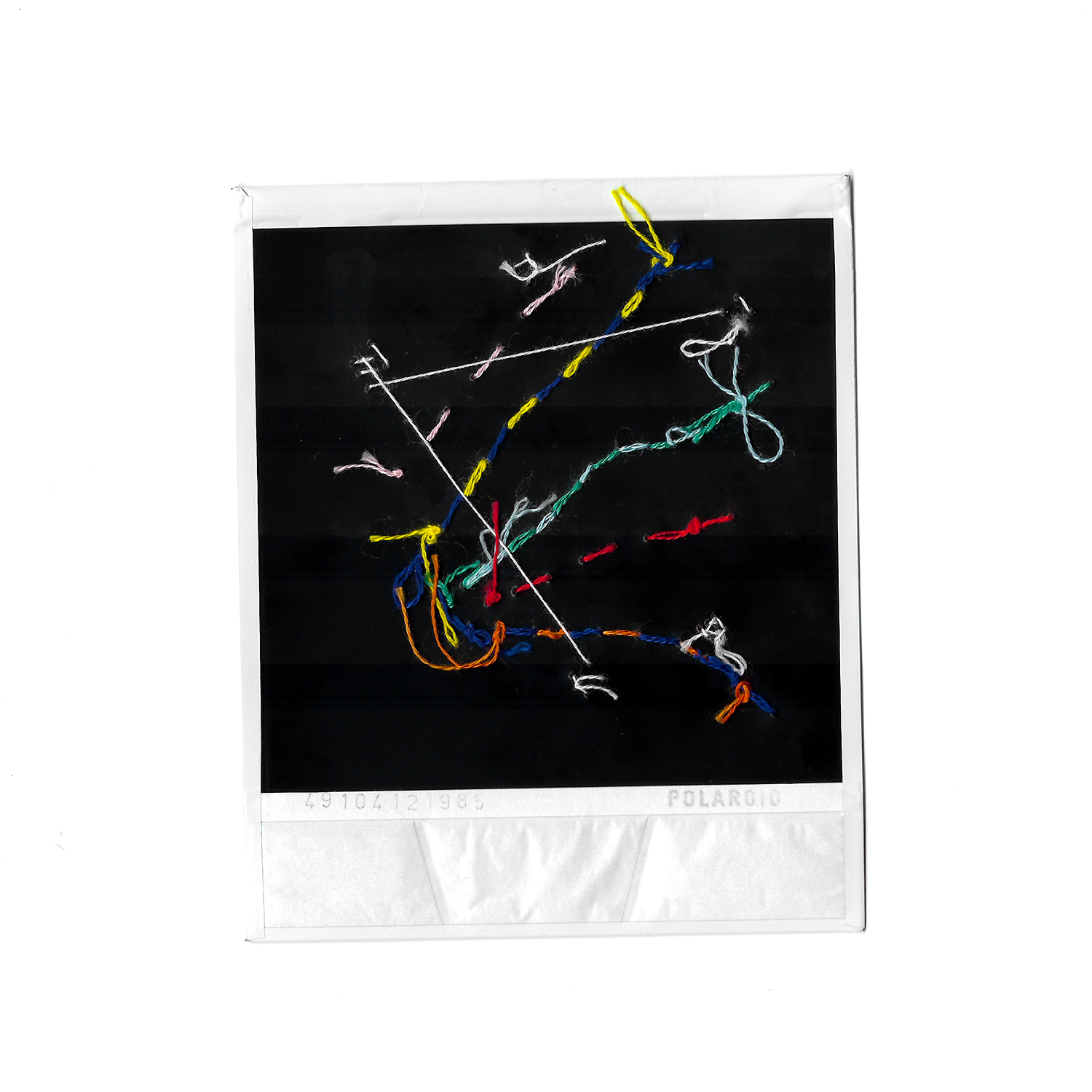 Underside of polaroid photograph with colourful embroidery sewn into it.