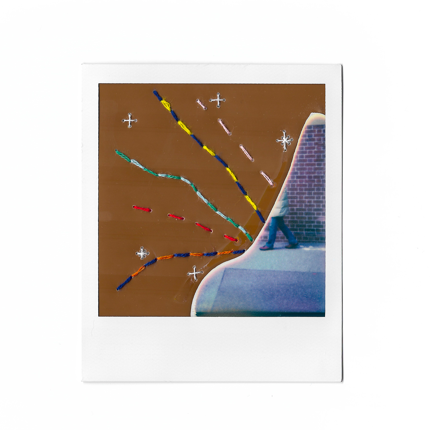 Spoiled polaroid photograph depicting part image of person walking against a brick background with colourful embroidery sewn into the photograph.