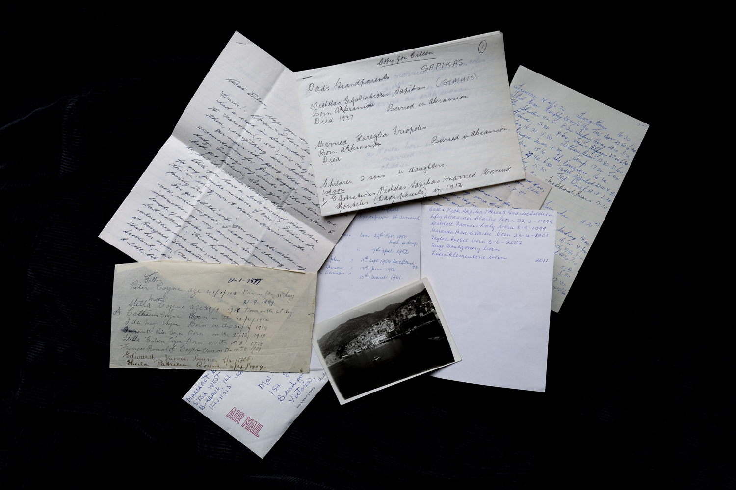 Colour photograph depicting an array of letters and a black and white photograph, scattered on a black surface.