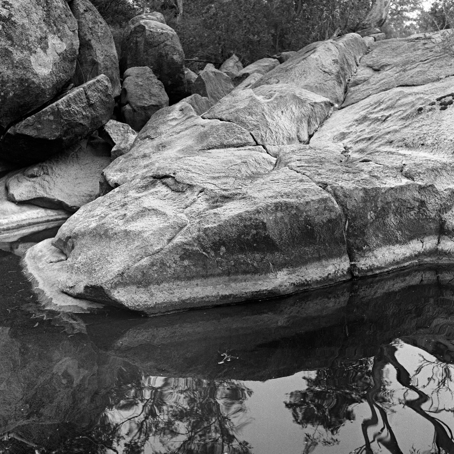 Black and white photograph depicting rock formations at a creek stream edge.