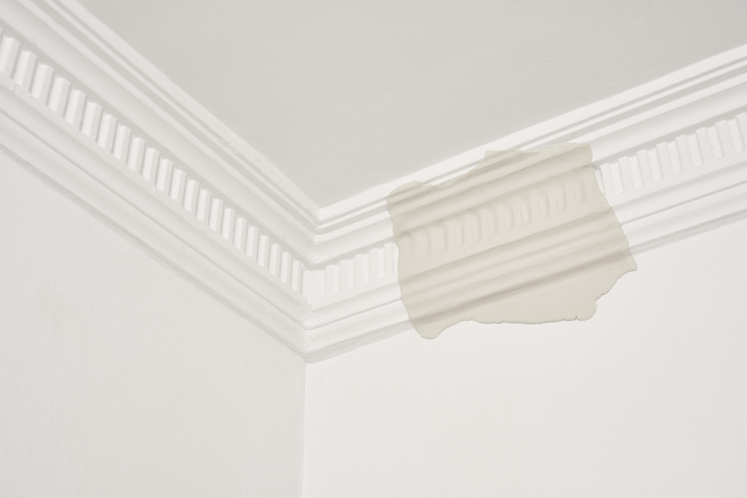 Thin sheet of aluminium pressed into the corner of a white door frame