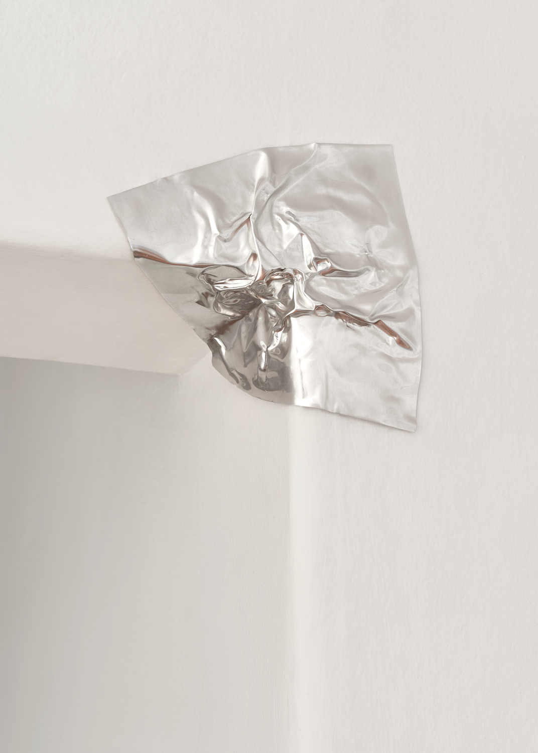 Thin sheet of aluminium pressed into the corner of a white door frame