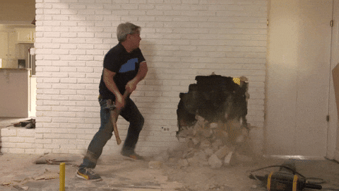 A looping GIF of a man smashing through a brick wall with a sledgehammer.