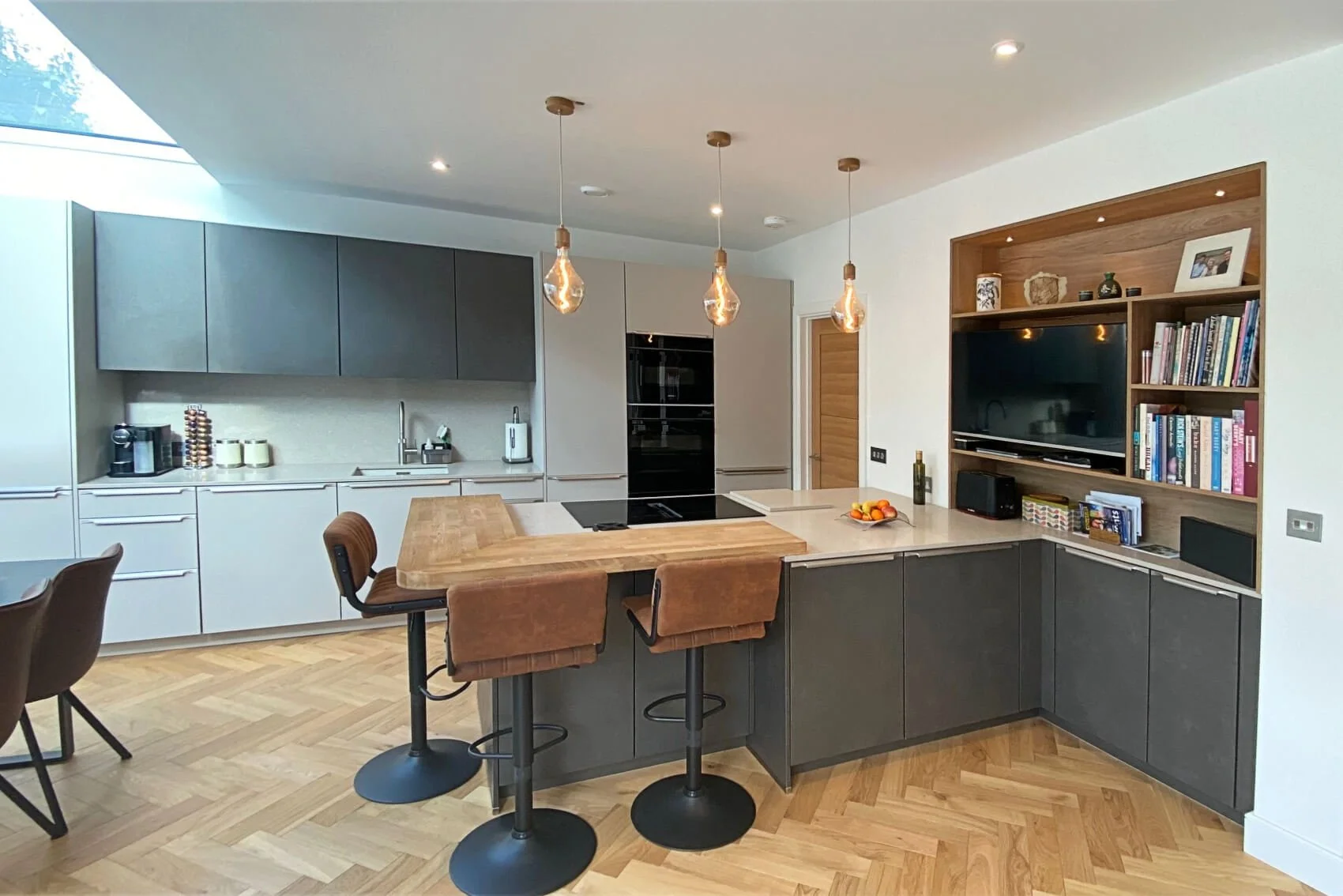 modern kitchen with dark cabinets, wood island, herringbone floor, and pendant lighting.