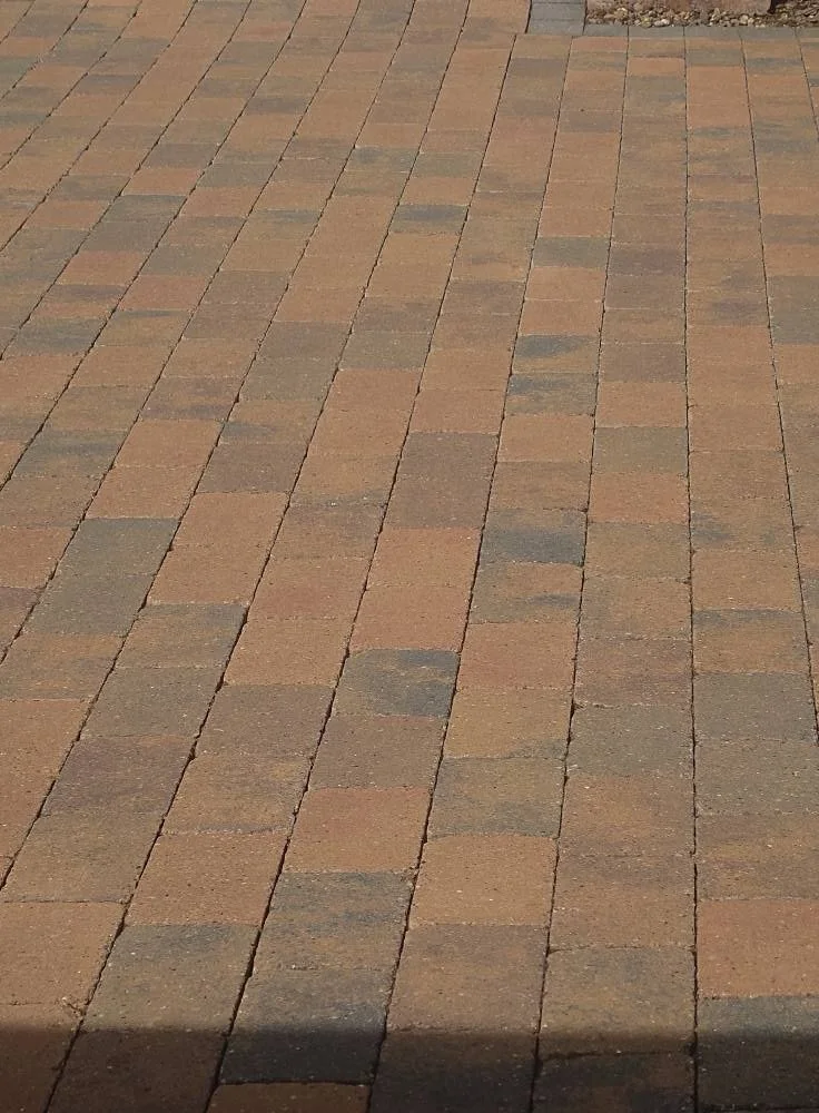 Image of a paved walkway made of rectangular bricks in shades of brown and gray.