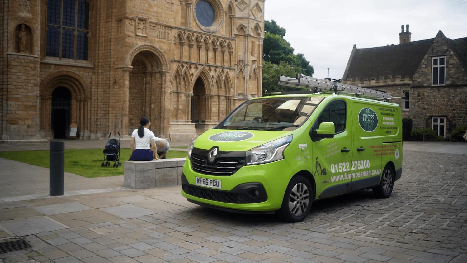Green moss man van driving past the cathedral in Lincoln