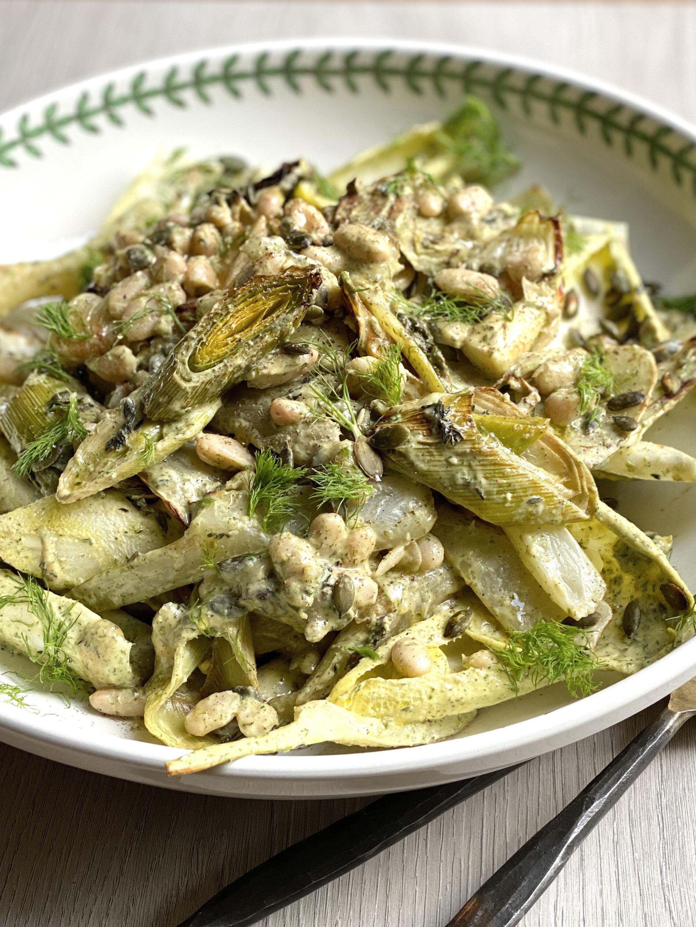 Roasted fennel and white bean salad with caper dressing in a green and white bowl