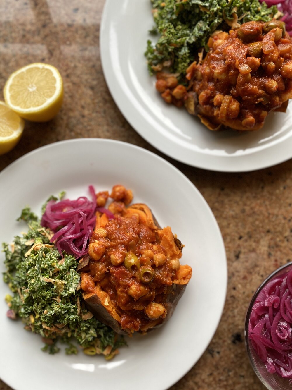 Two plates of baked sweet potatoes loaded with chickpea tagine