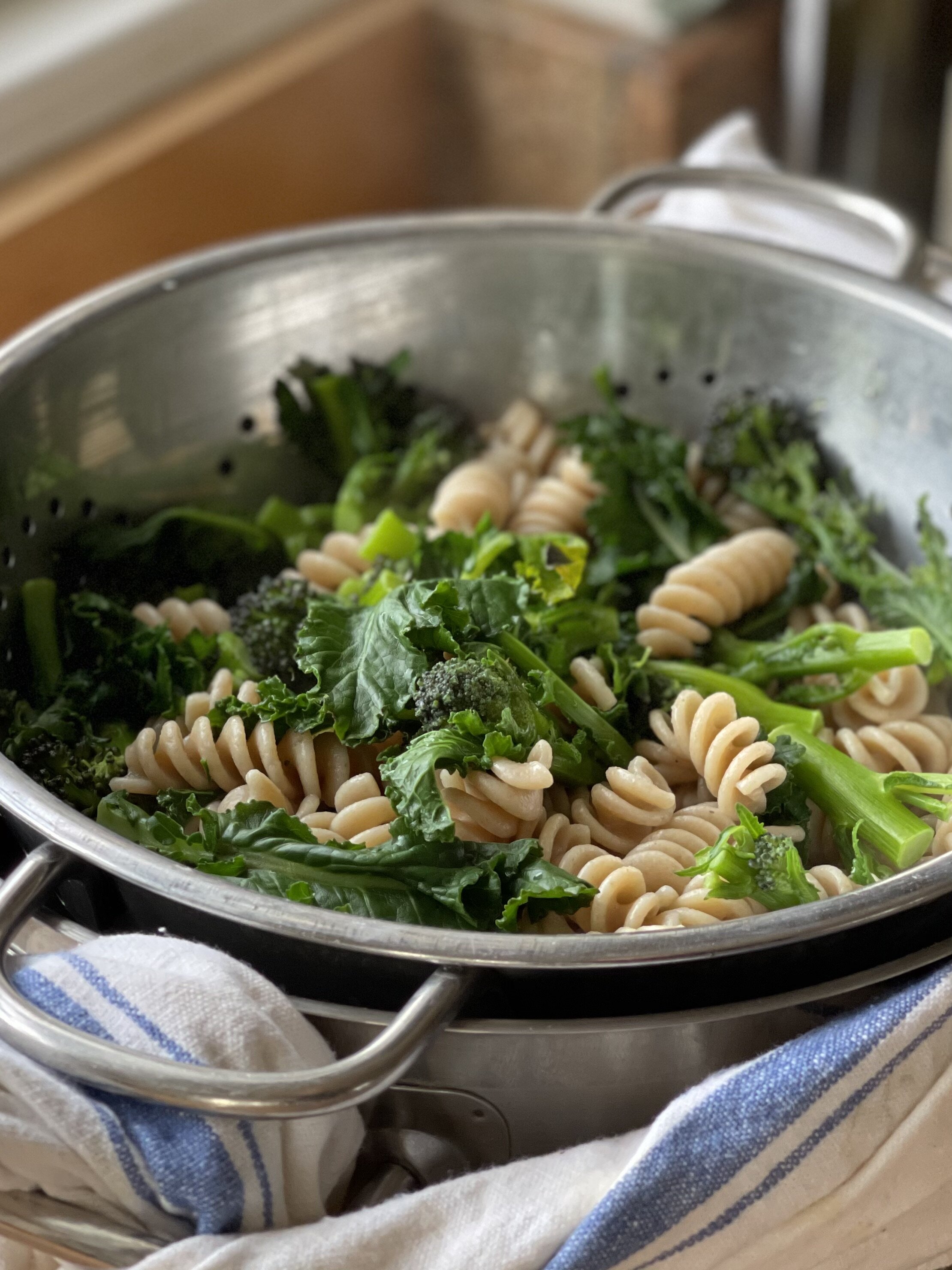 A colander of pasta and purple sprouting broccoli