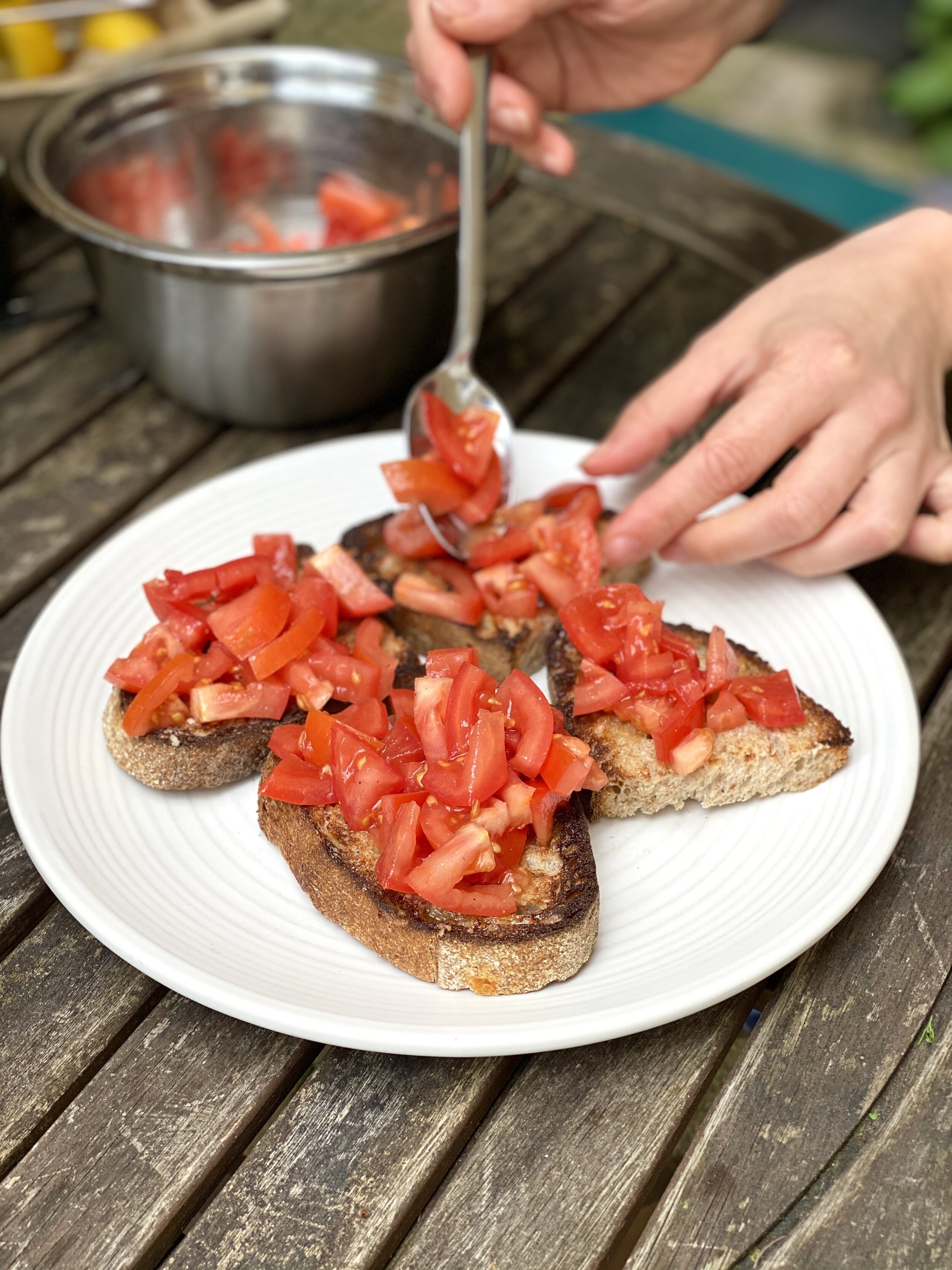 Spooning tomatoes onto charred sourdough