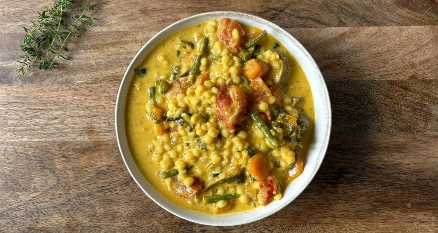 Warm golden vegetable stew in a white bowl — nourishing postpartum meal by Moongold, Berlin
