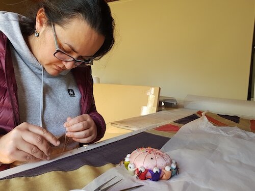 Stitch-mounting the flag onto a custom backing, prior to re-housing. Lara RSL.
© Tiaki Objects Conservation.