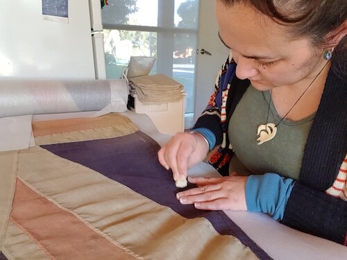 Cleaning the surfaces of the flag. Lara RSL.
© Tiaki Objects Conservation.