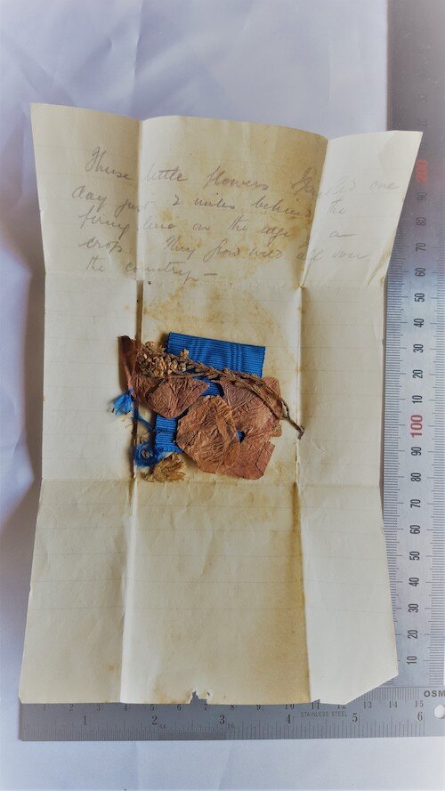 Before treatment – a handwritten letter, with a medal ribbon and desiccated flower. Private Collection. © Tiaki Objects Conservation.