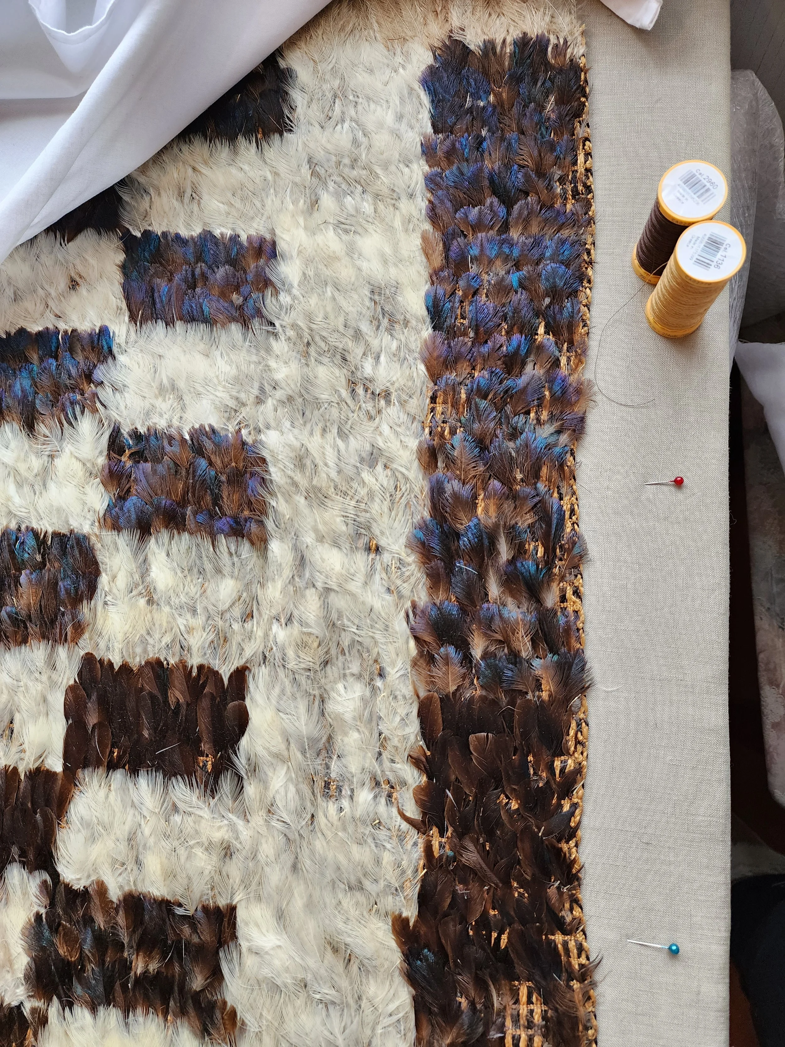 Close-up of Indigenous feather textile undergoing conservation treatment on a support surface