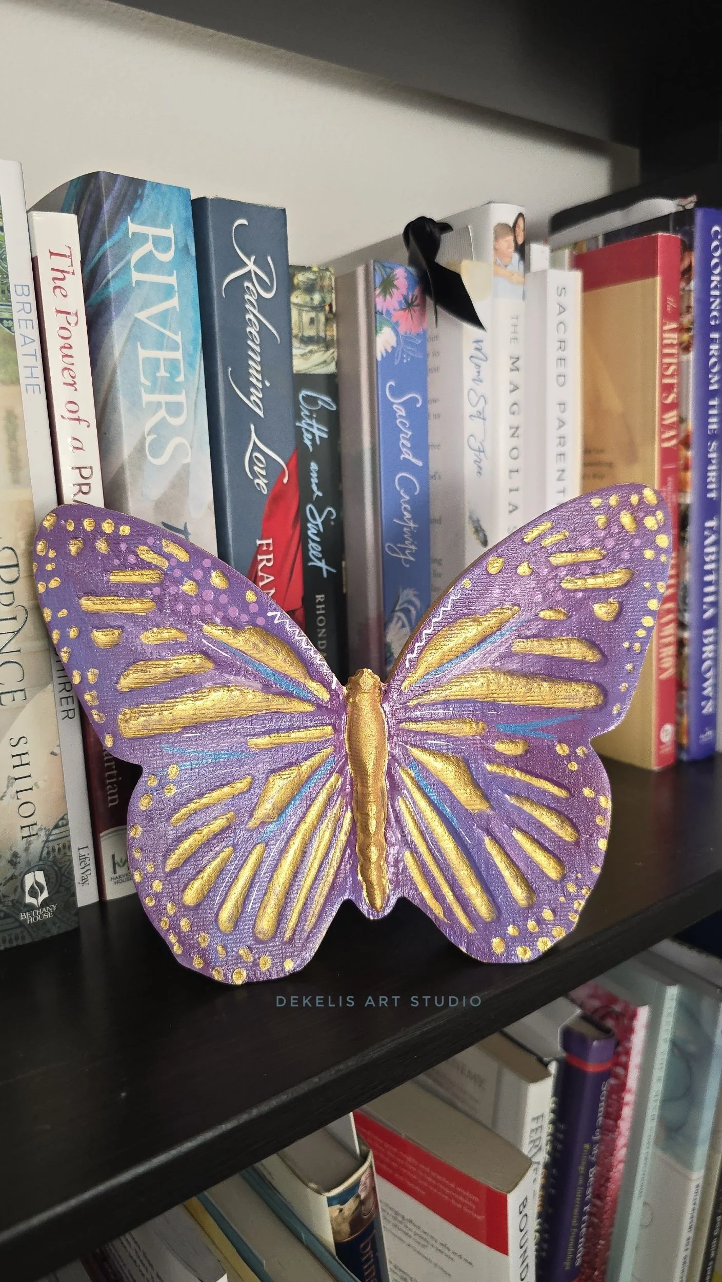 Brighten any space with this hand-painted wooden butterfly, finished in shimmering metallic gold, rich purple, blue and white.