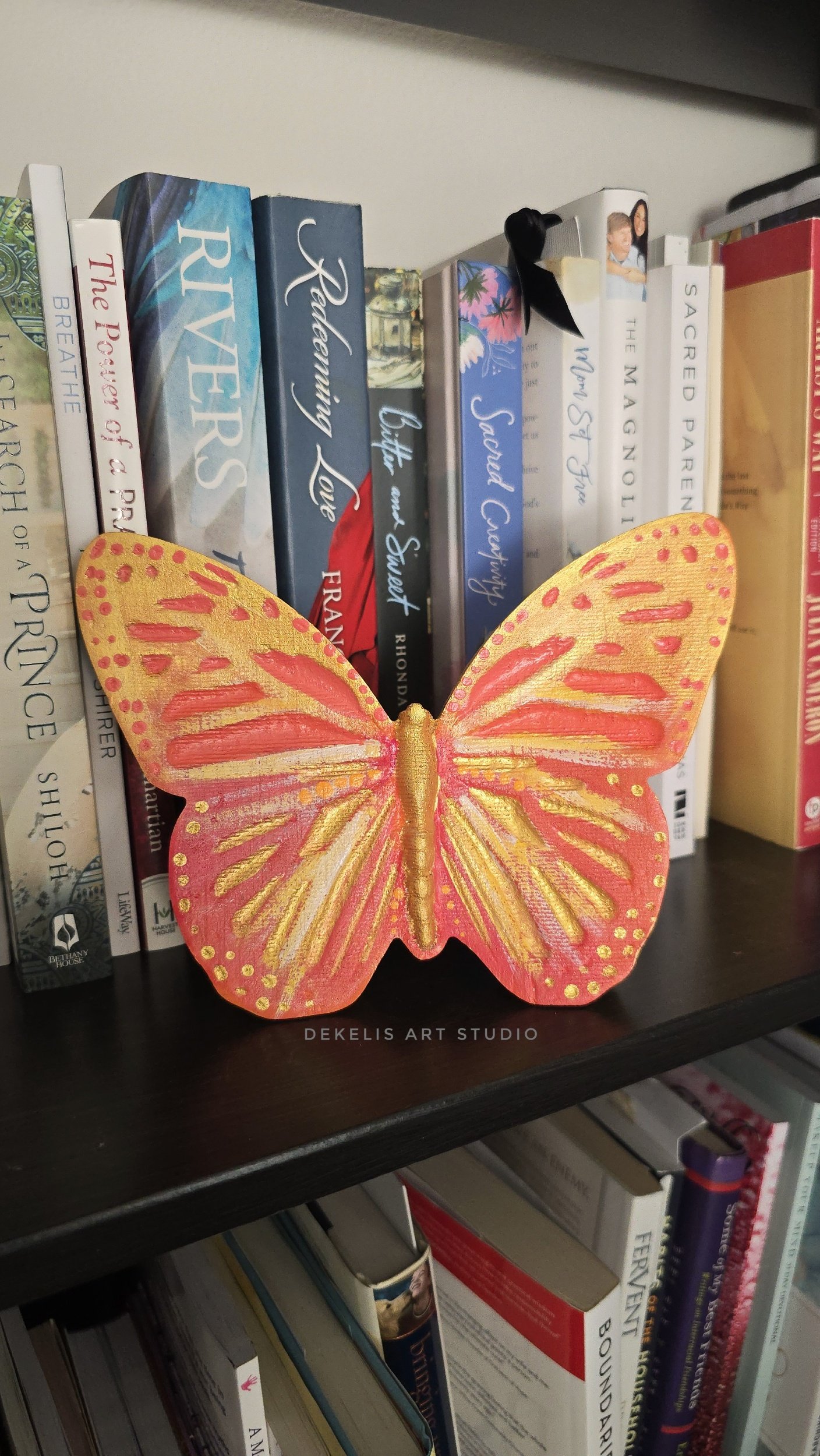 Brighten any space with this hand-painted wooden butterfly, finished in shimmering metallic gold, warm orange, coral, soft yellow and white.