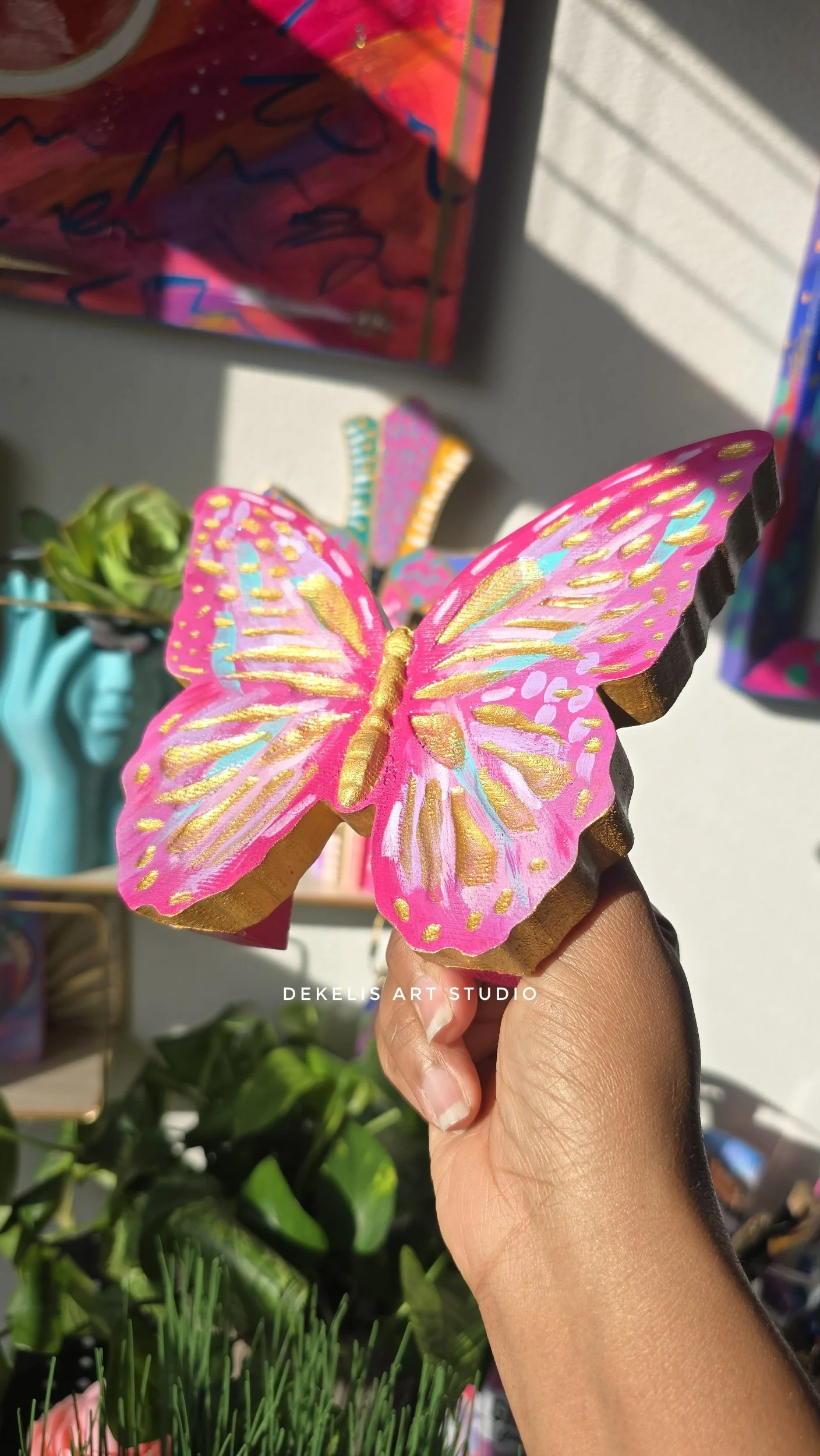 Brighten any space with this hand-painted wooden butterfly, finished in shimmering metallic gold, sweet pink, lavender, turquoise and white.