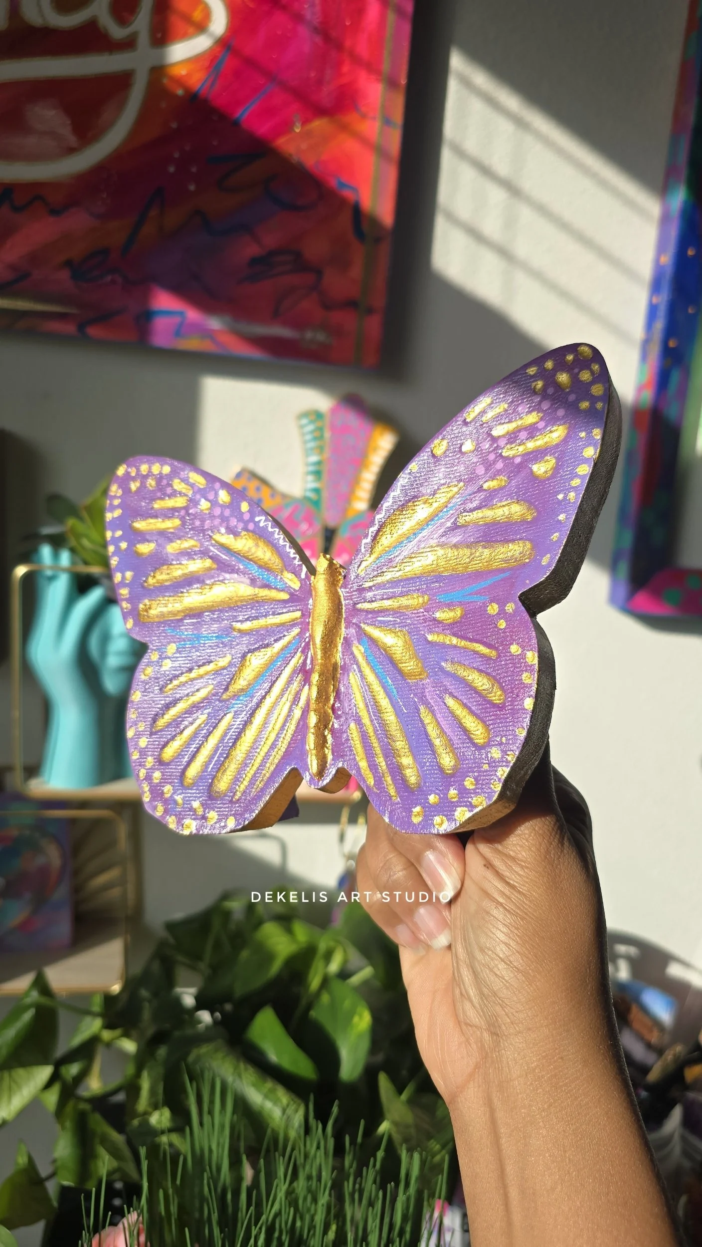 Brighten any space with this hand-painted wooden butterfly, finished in shimmering metallic gold, rich purple, blue and white.
