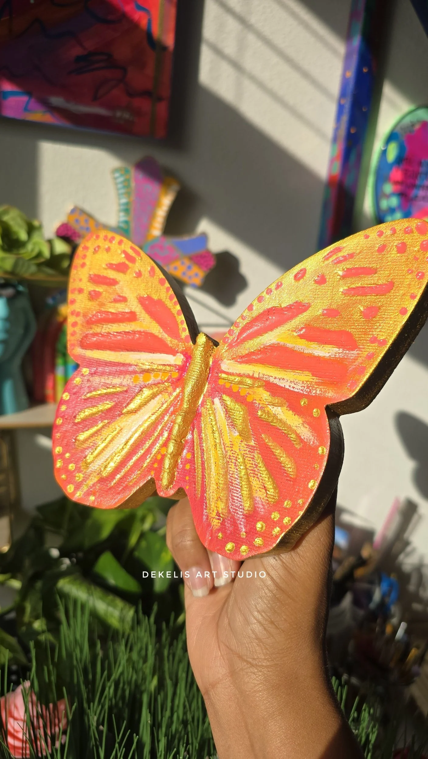 Brighten any space with this hand-painted wooden butterfly, finished in shimmering metallic gold, warm orange, coral, soft yellow and white.