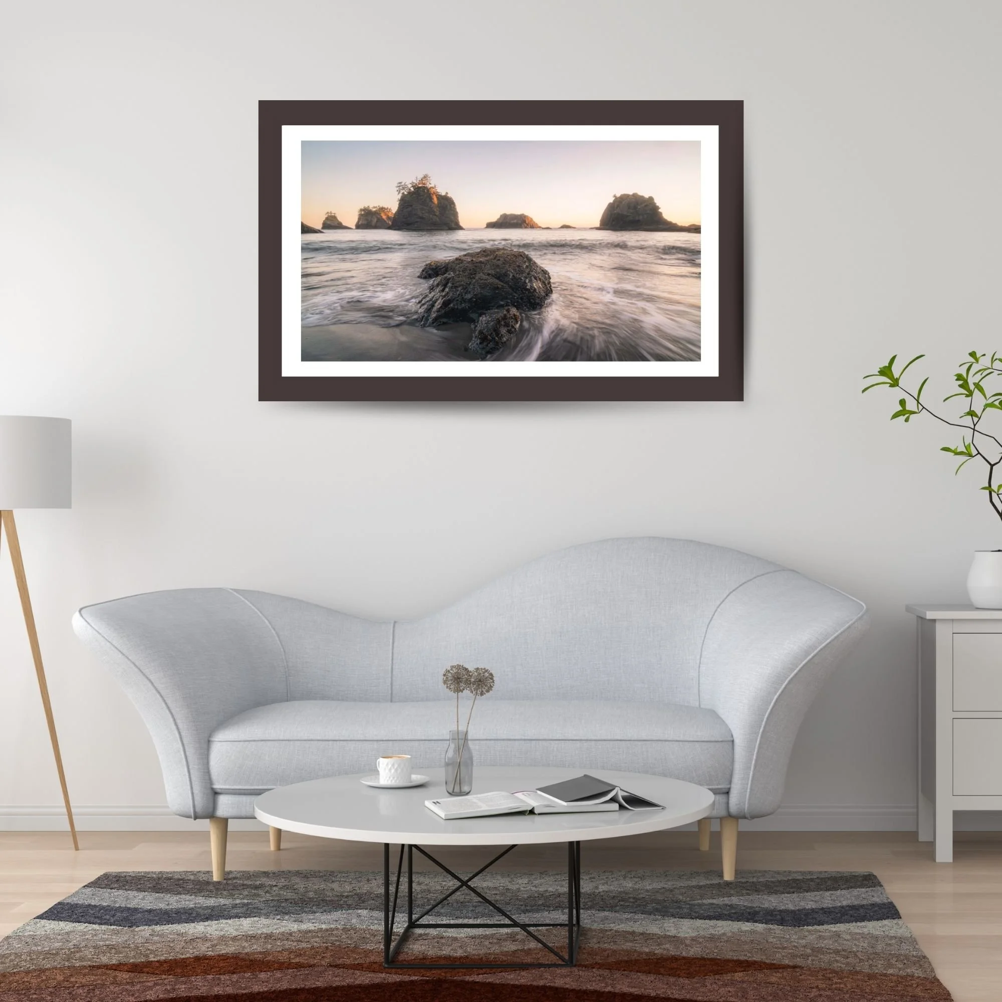 A mockup photo of the a framed landscape image hanging in the living room above a couch