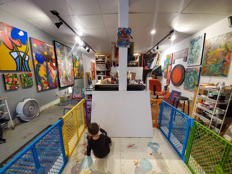An art studio with bold, vibrant, and abstract artworks hanging.
