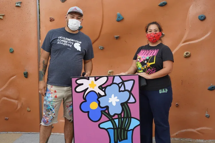 Albert Gonzales stands with a collector of his holding up a wabi sabi painting during the pandemic.