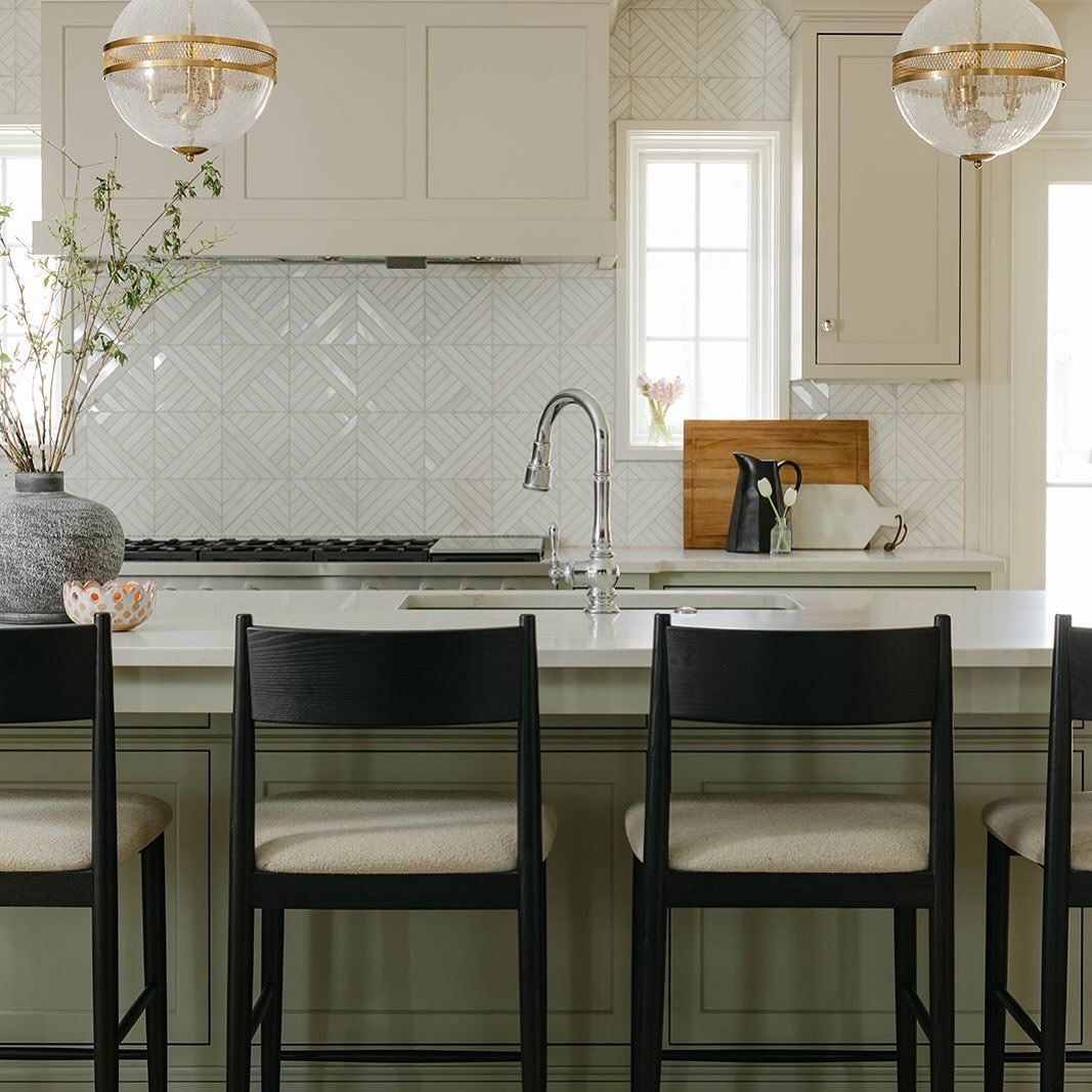 Soft femininity shines in this serene kitchen. Neutral greens and taupe warm up the cabinets with a pop of shine from the mosaic marble back splash and these crackled glass pendants have a nostalgic feel, but in an updated way. 

Designed and ruled b