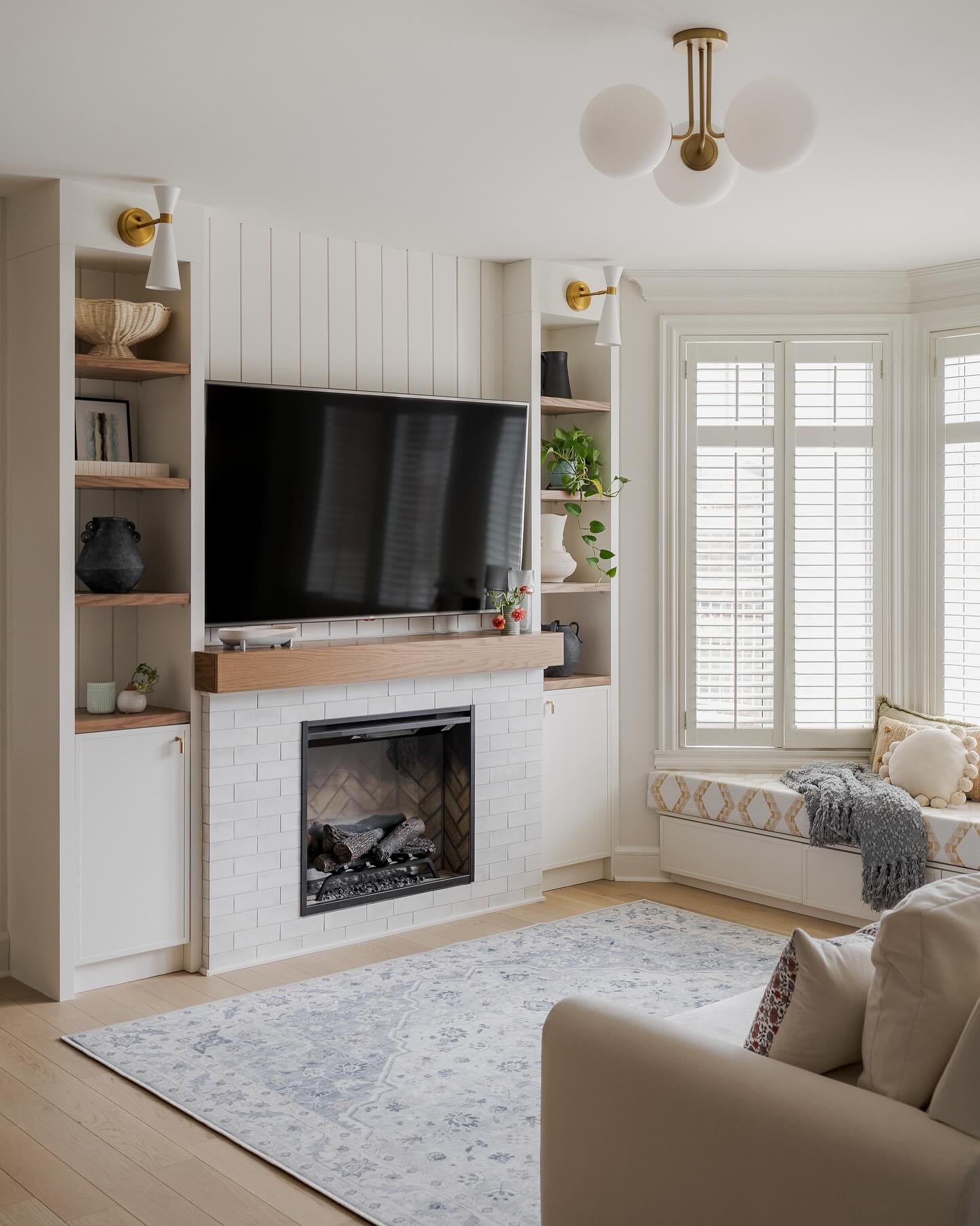 This used to be a blank wall and an empty window bay. 

These clients really wanted to re-create the cozy vibes of their chalet in the city. We decided to add an electric fireplace for ambience, and fill this empty bay window with a large built-in se