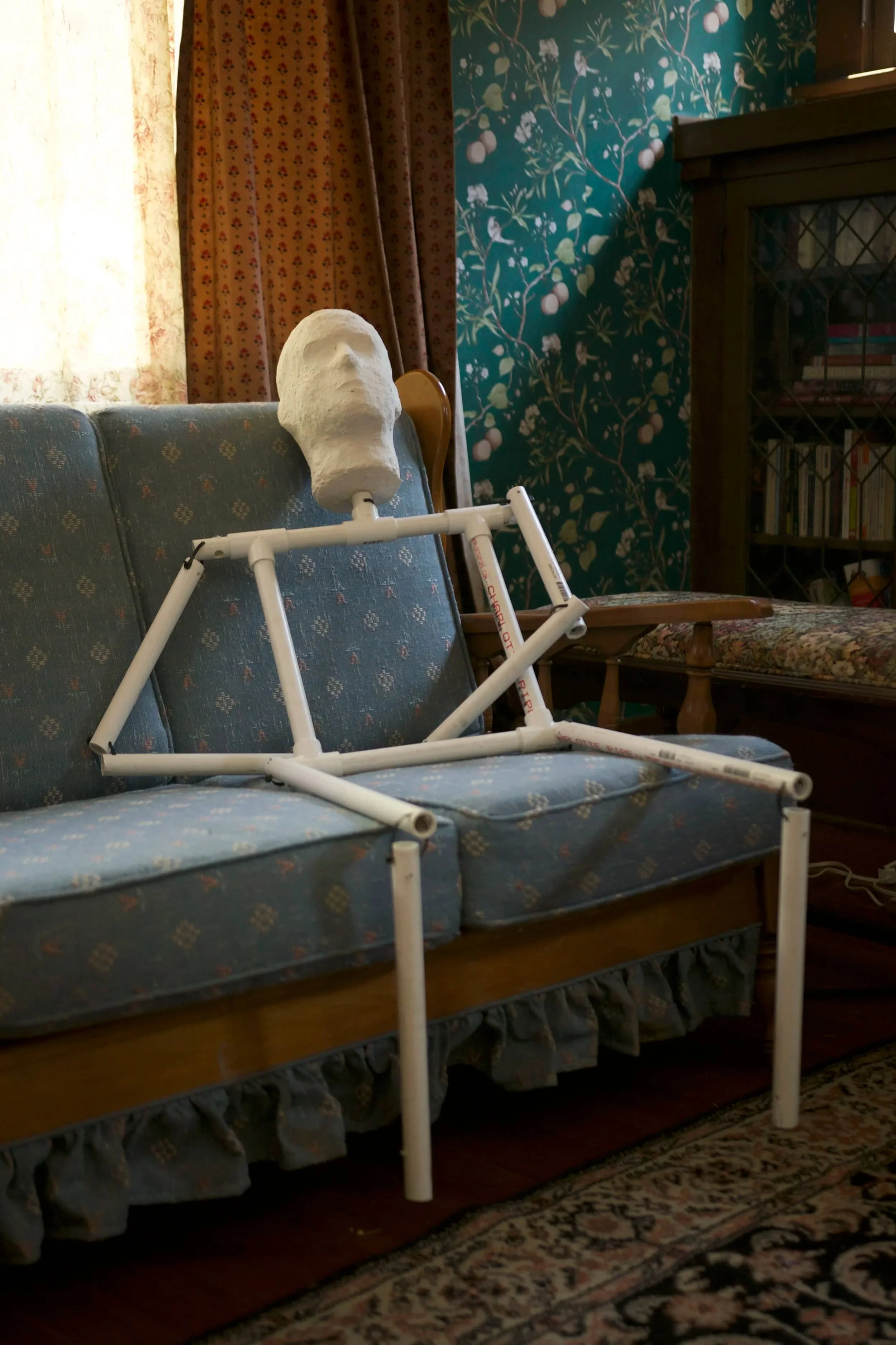 Hand-crafted prop sculpture of a human face on a PVC frame, staged within a cozy vintage set - part of Keagan Roberson’s costume and prop design work for Shedding Angels.