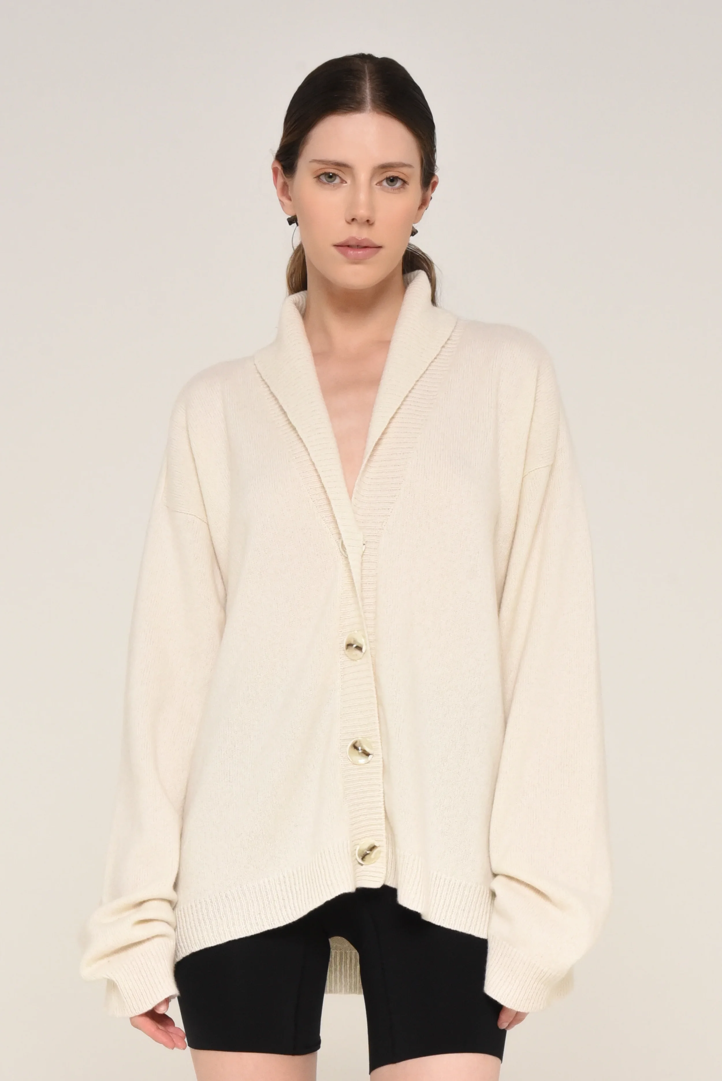 Model wearing a cream oversized cardigan with large buttons and black shorts - designed in collaboration with Keagan Roberson.