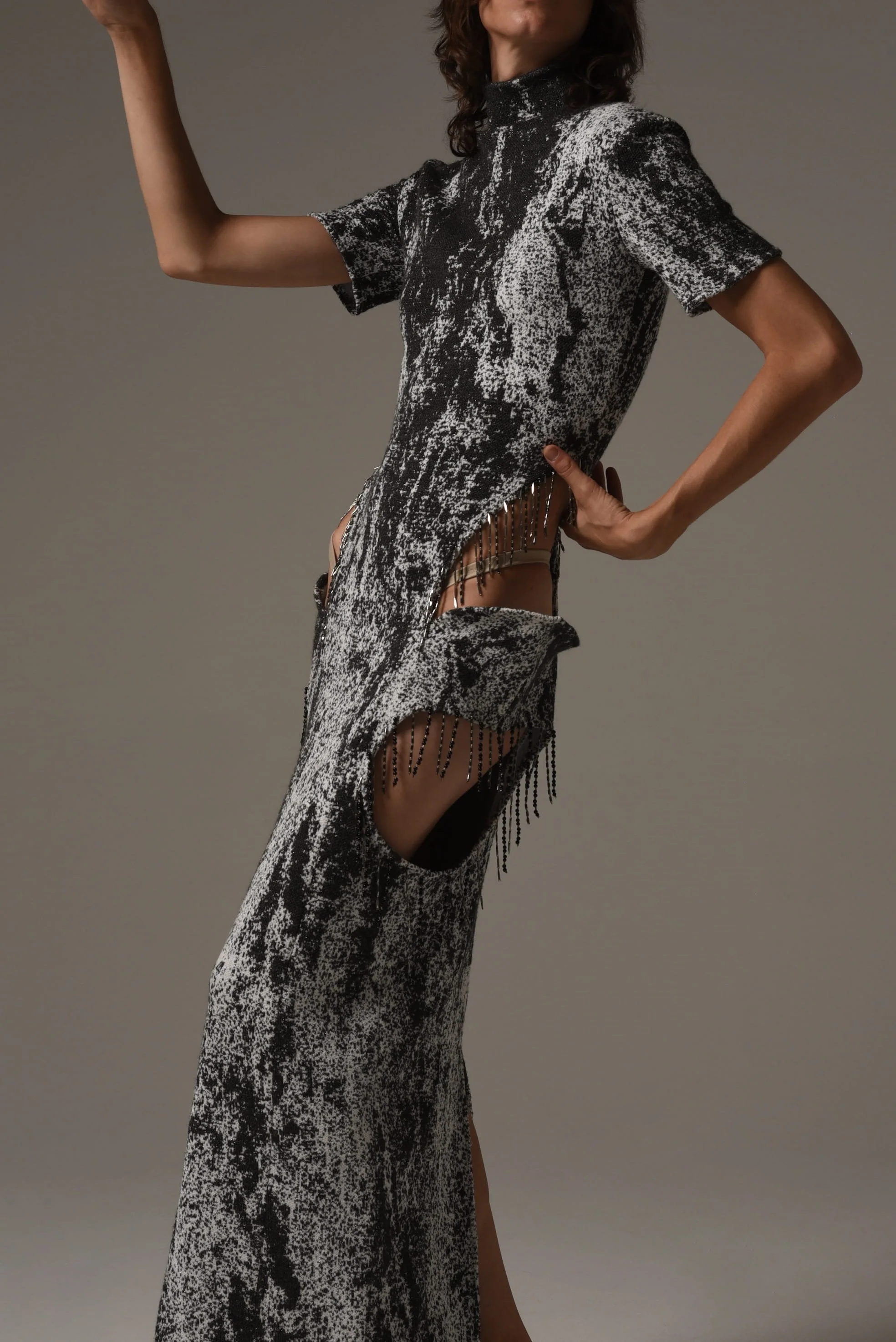 Model wearing a black-and-white dress with fringe and cutout details from Keagan Roberson - bold sculptural pose captured in studio.