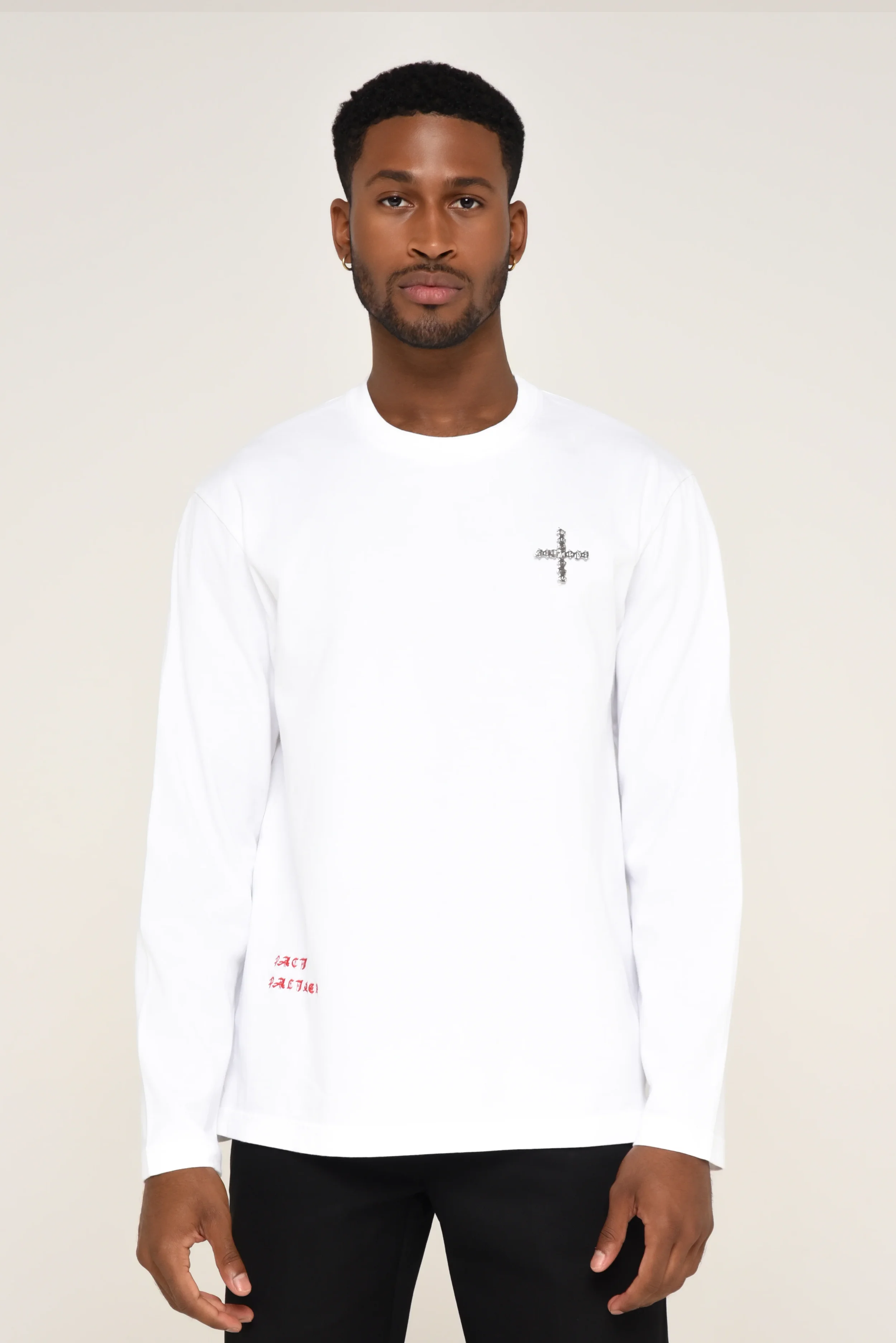 Model wearing a white long-sleeve shirt with an embellished cross motif and red sleeve text - designed in collaboration with Keagan Roberson for Seymone.