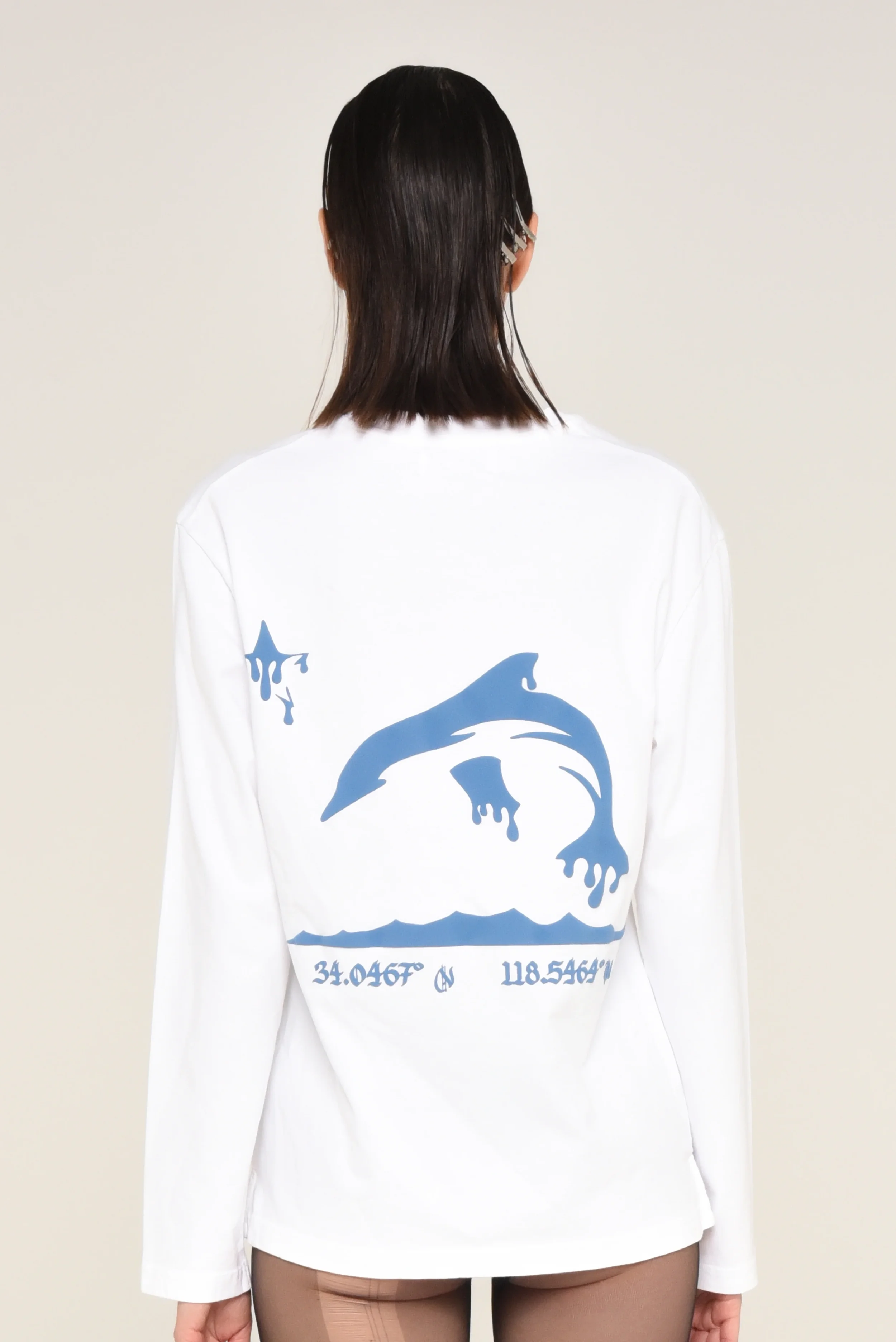 Back view of a white long-sleeve shirt featuring a blue shark and wave graphic with printed coordinates - designed in collaboration with Keagan Roberson for Seymone.