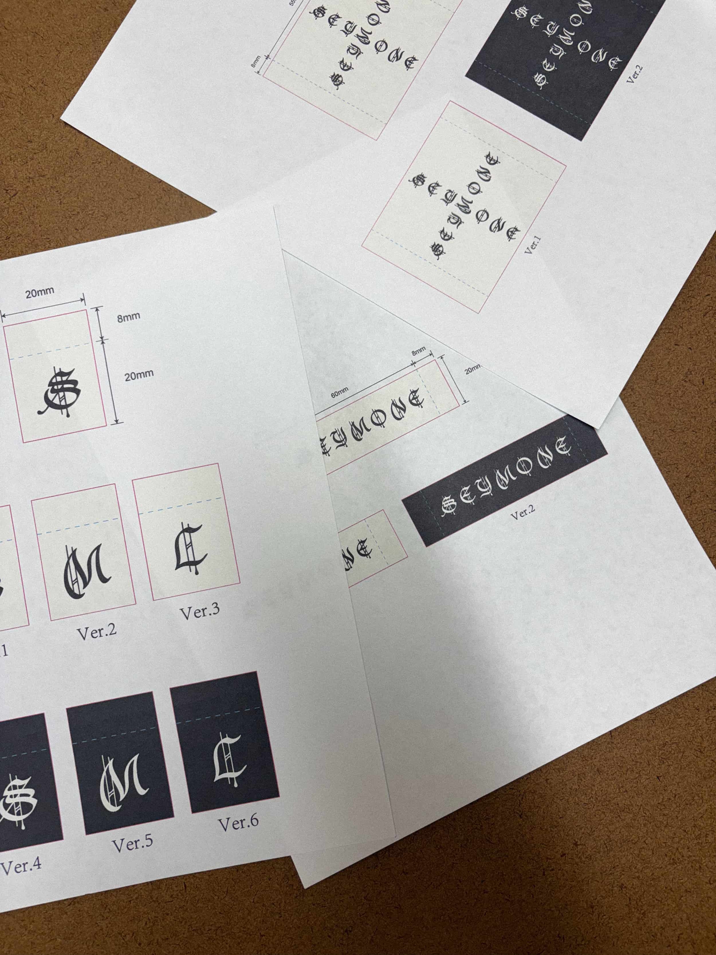 Printed design sheets showing gothic-style text variations and layout measurements for SEYMONE branding - designed in collaboration with Keagan Roberson.