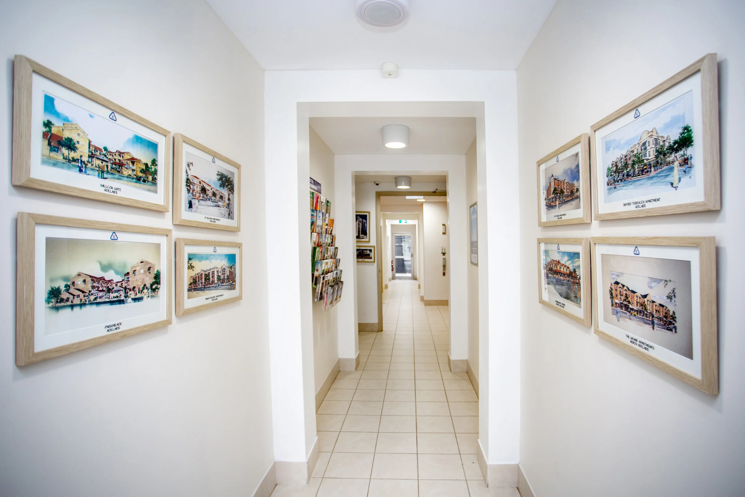 Interior hallway with framed architectural illustrations on walls and brochures in a rack.
